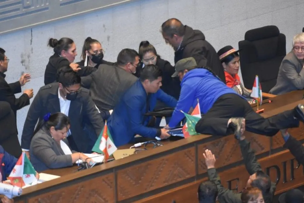 Una de las asambleístas del ala "evista" se trepa a la testera con ayuda de sus colegas. Foto: APG