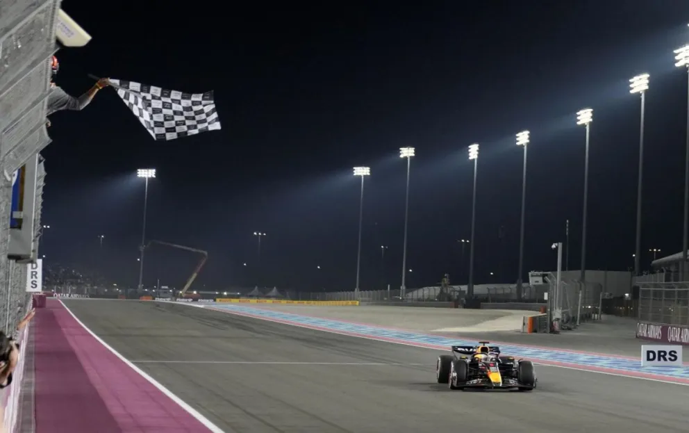 Le bajan la bandera a cuadros a Max Verstappen, al mando de su Red Bull, tras ganar el GP de Qatar. Foto: EFE