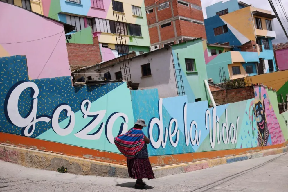 Imagen del 26 de noviembre de 2024 de una mujer junto a un mural en el barrio de Chualluma, en La Paz (Bolivia). Foto: EFE