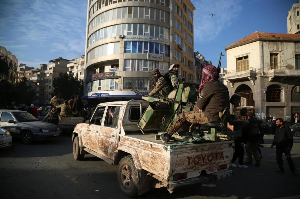 Rebeldes sirios en la parte trasera de un vehículo mientras la gente celebra en las calles de Homs, Siria, la caída del gobierno de Bachar al Asad el 8 de diciembre de 2024. Foto: EFE