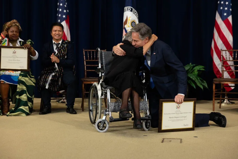 El secretario de Estado de EE. UU. Antony J. Blinken se arrodilla y abraza a Carvajal en la entrega del reconocimiento. Foto. red social X de A. J. Blinken.