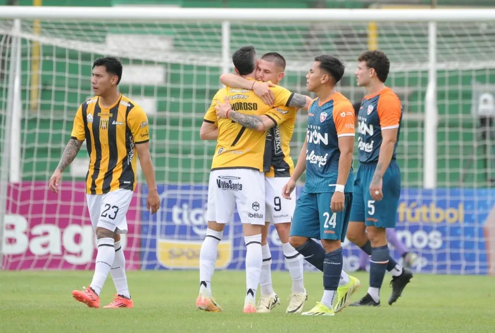 Sebastián Guerrero es felicitado por Amoros tras convertir el primer gol. Lo lamentan los jugadores de Royal Pari. Foto: APG