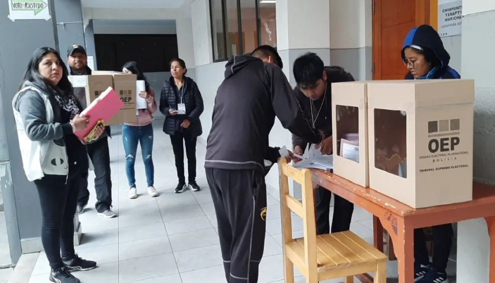 Una notaria supervisa el voto asistido de una mesa, mientras los jurados de otra mesa esperan su turno. Foto: Mirna Echave