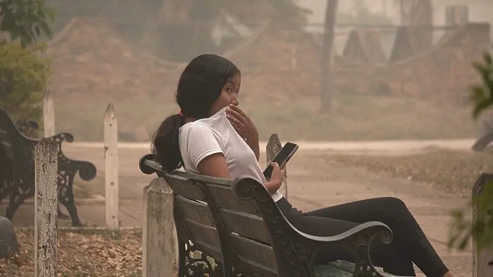 Una joven trata de taparse la boca para no respirar el humo de los incendios. Foto: Captura del documental