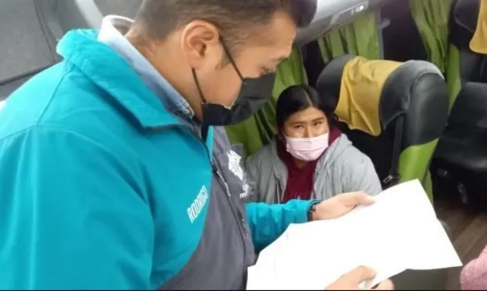 Un funcionario revisa el permiso de viaje de un menor de edad en un bus. Foto: AMUN