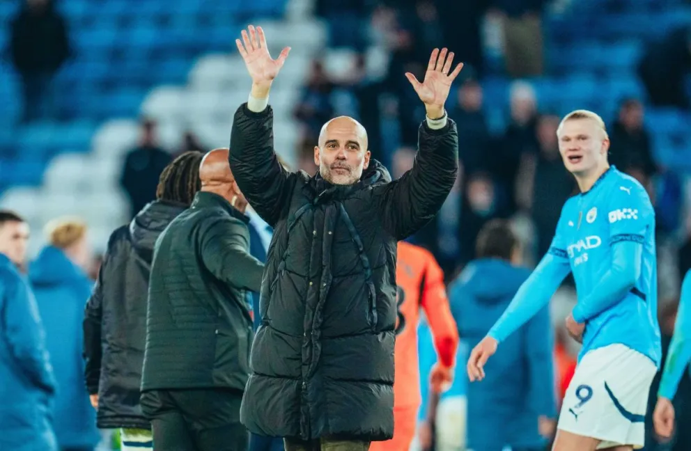 Pep Guardiola, el DT del City, saluda a los hinchas de su club. Lo observa metros atrás Erling Haaland. Foto: club Manchester City