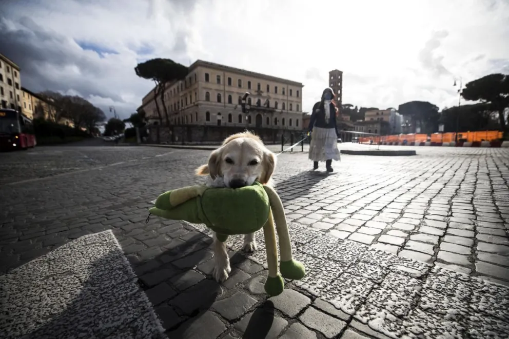 En la imagen de archivo, una mujer pasea a su perro en una calle durante el encierro navideño por la pandemia, en Roma, Italia. Foto: EFE