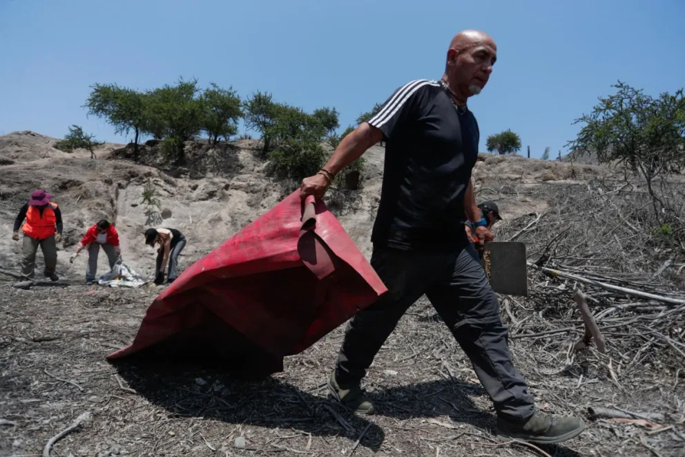 Fotografía del 27 de diciembre del 2024 de voluntarios despejando uno de los quince sitios georreferenciados en el Cerro Chena, comuna de San Bernardo, en Santiago de Chile. Foto: EFE