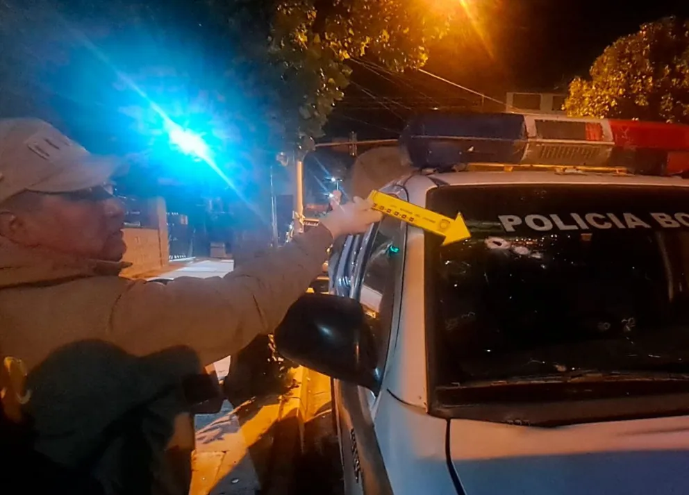 Un efectivo muestra el impacto que sufrió el parabrisas de un vehículo policial. Foto: Policía Boliviana 