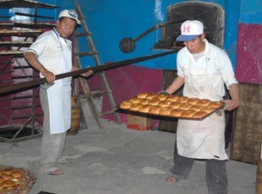 Dos panaderos trabajan en un horno en la elaboración de pan. Foto: Opinión