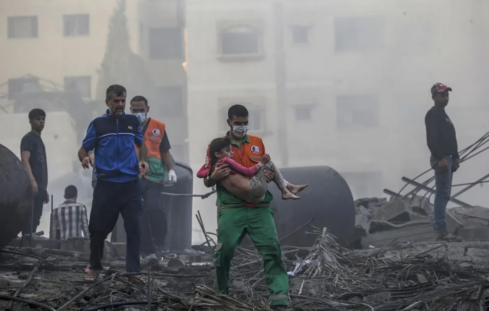 Un palestino carga a una niña herida en una zona destruida tras los ataques aéreos israelíes en Gaza, el 25 de octubre de 2023. Foto: EFE