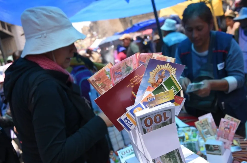 Una compradora junto a billetes y otros objetos de la feria de la Alasita. Foto: APG 