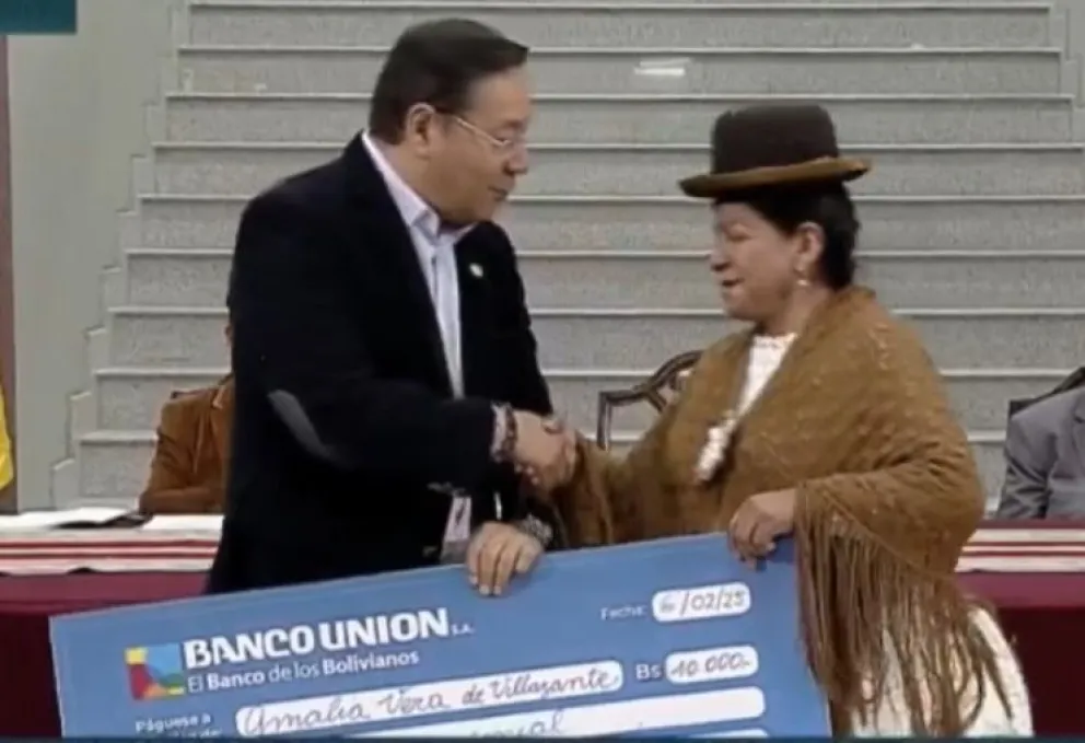 El presidente Luis Arce entrega uno de los cheques a Amalia Vera. FOTO: ABI