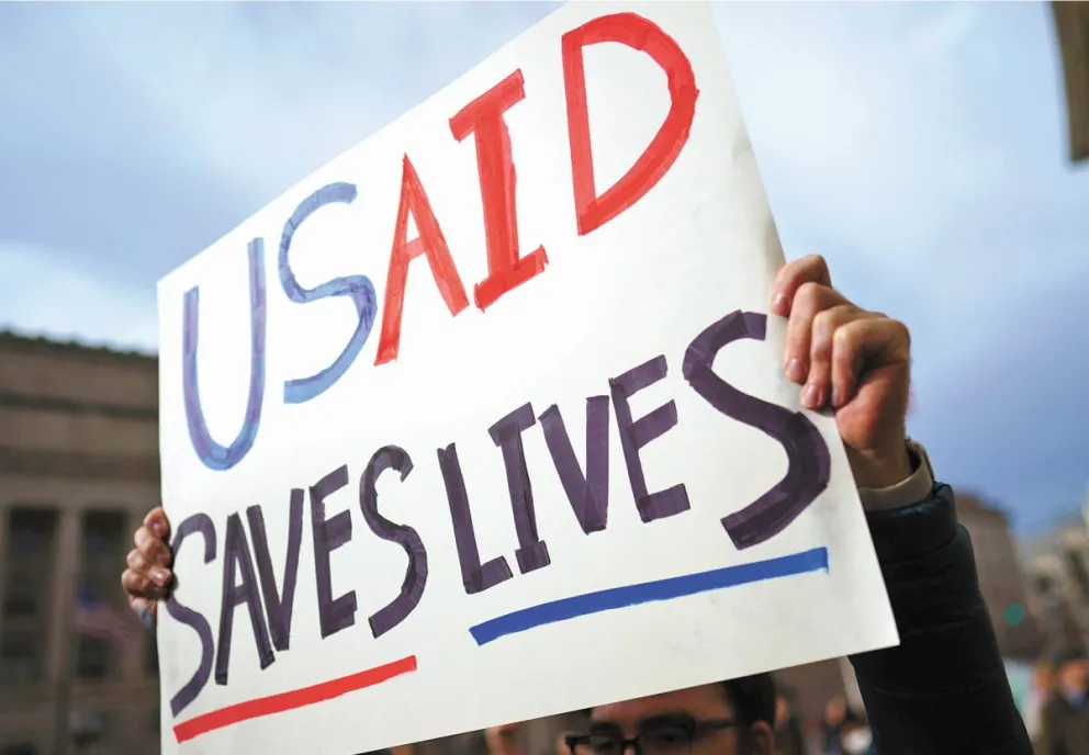 Un manifestante sostiene un cartel en el que se lee “Usaid salva vidas”, frente a la agencia, durante una manifestación en Washington. Foto: EFE