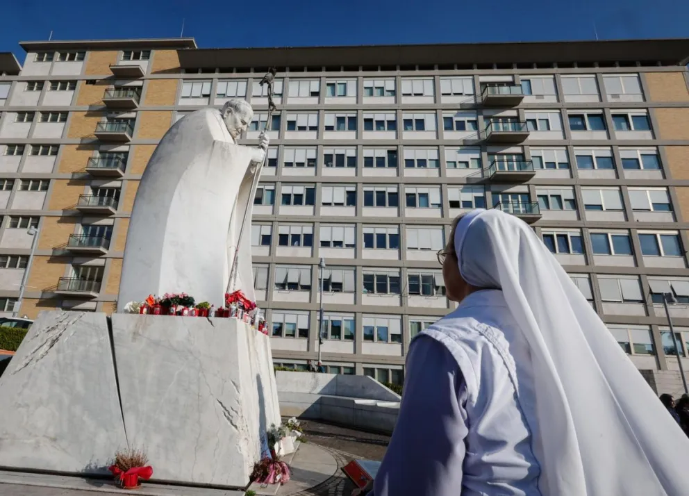 Una monja reza ante una estatua del Papa San Juan Pablo II fuera del Hospital Universitario Gemelli. Foto: EFE