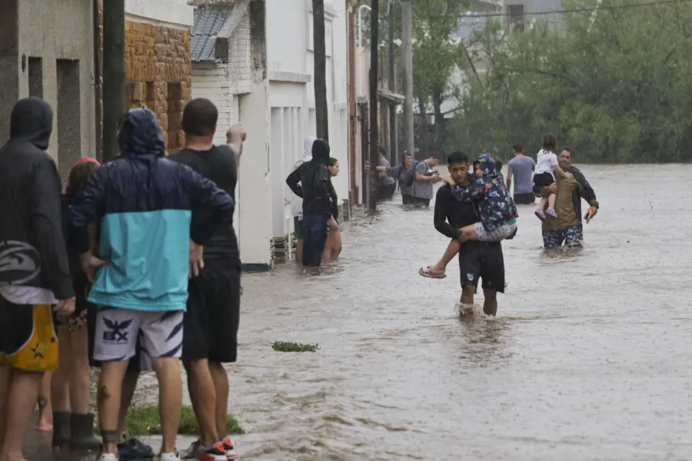 Varias personas caminan en medio de una inundación debido a fuertes lluvias este viernes, en Bahía Blanca (Argentina). Foto: EFE