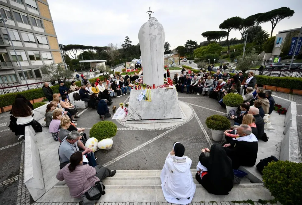 Un grupo de peregrinos rusos se reúne junto a la estatua de Juan Pablo II en la entrada del Hospital Gemelli, donde está hospitalizado el Papa Francisco, en Roma. Foto: EFE