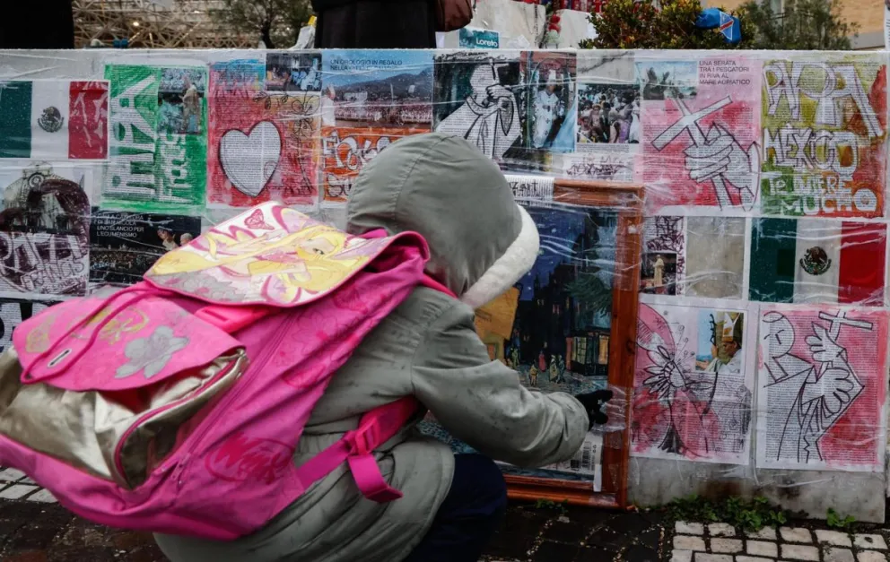 Un niño mira dibujos y fotografías colocadas en la parte inferior de la estatua de Juan Pablo II junto al Hospital Gemelli, donde el papa Francisco permanece hospitalizado, en Roma, el 12 de marzo de 2025. Foto: EFE