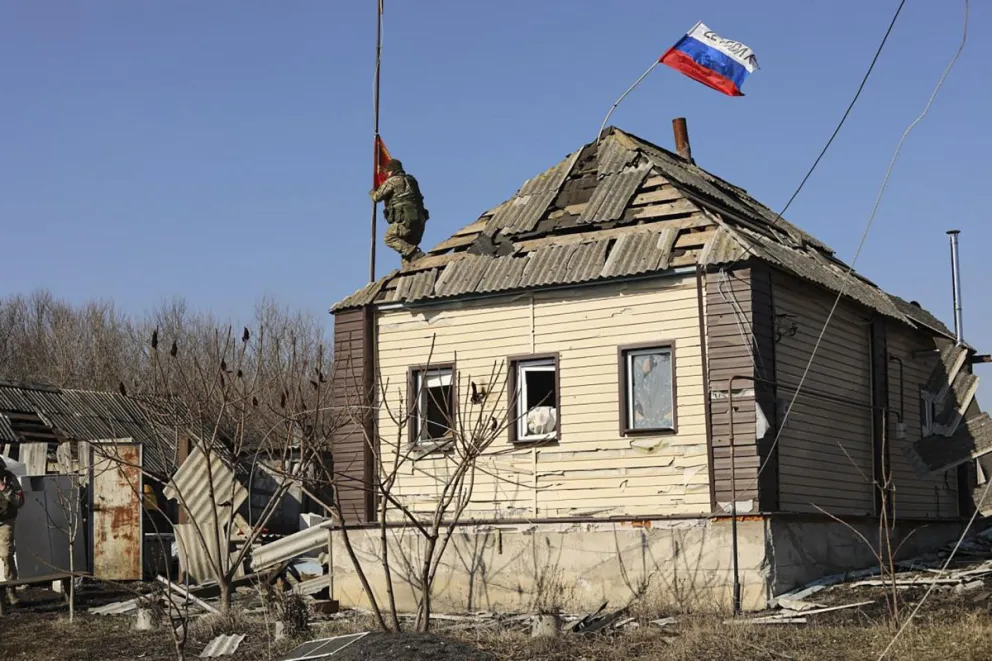 Un soldado ruso instalando una bandera roja en el techo de un edificio privado dañado en un pueblo de la región de Kursk, Rusia. Foto: EFE