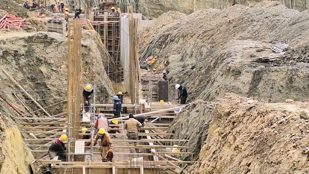 Obreros trabajan en la construcción del muro de contención que sostendrá toda la estructura. A la derecha está el área asignada para las tres canchas.