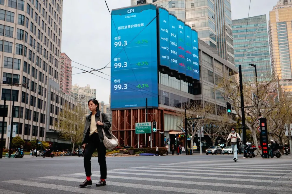 Personas en una calle cerca de pantallas que muestran datos bursátiles y económicos en Shanghái, China. Foto: EFE