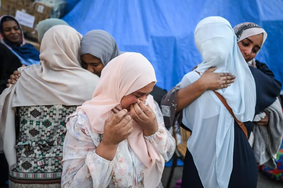 Mujeres refugiadas sudanesas se abrazan y lloran en un punto de reunión. Foto: EFE