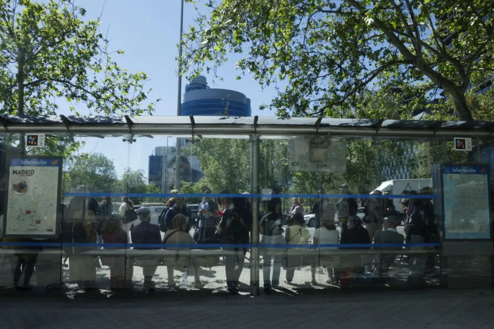 Madrileños esperan un bus en una parada. Fotos: EFE