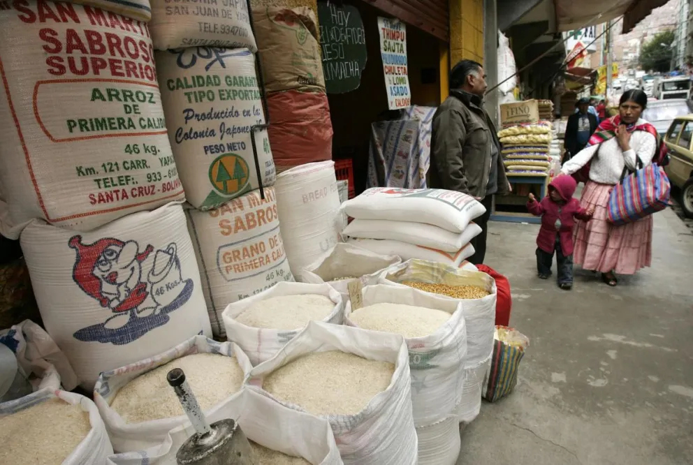 Fotografía de archivo de una mujer aimara al pasar por una venta de arroz, en La Paz (Bolivia). Foto: EFE