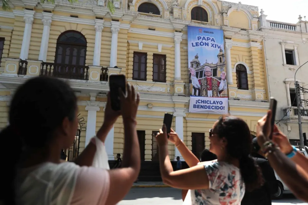 Personas toman fotos con sus teléfonos a una imagen del papa León XIV este sábado en Chiclayo (Péru). Foto: EFE