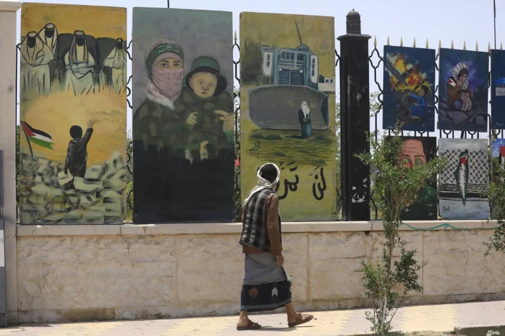Una persona pasa junto a una valla adornada con obras de arte pro-palestinas en Saná, Yemen. Foto: EFE