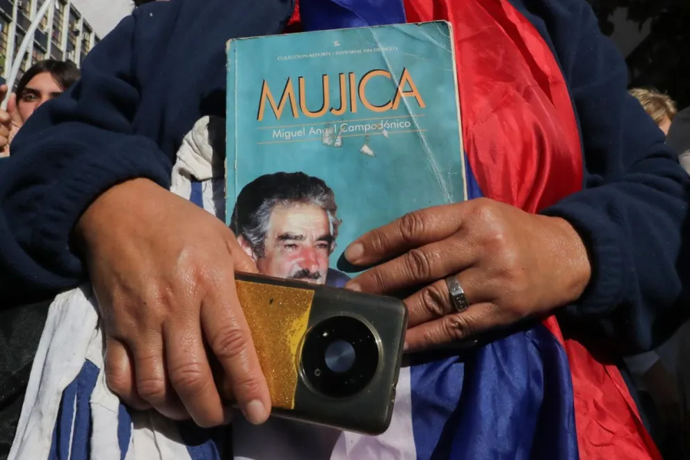 Una persona sostiene un libro durante el cortejo fúnebre del expresidente uruguayo José Mujica este 14 de mayo de 2025, en Montevideo (Uruguay). Foto: EFE