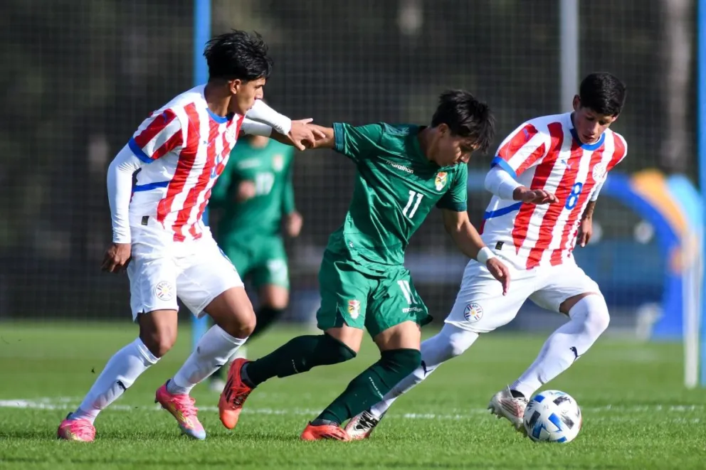 El boliviano Santos García (11) se saca la marca de dos jugadores paraguayos. Foto: La Verde-FBF