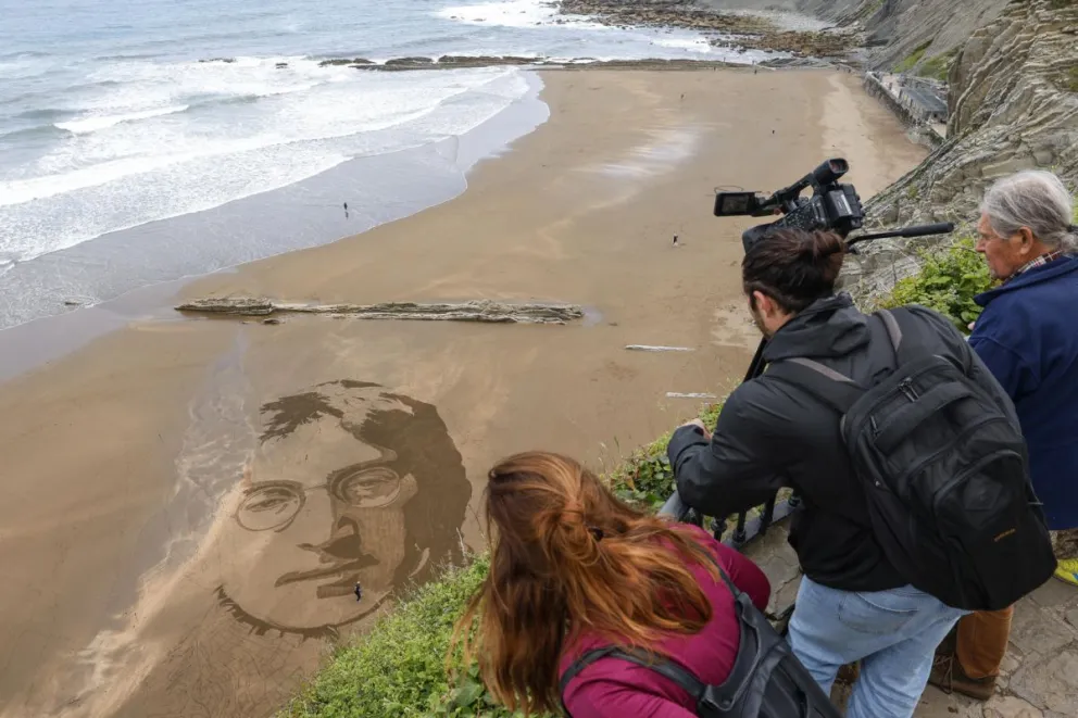 El artista peruano Germán Cedano trabaja en una playa del norte de España, donde graba en la arena la imagen del músico John Lennon. Foto: EFE
