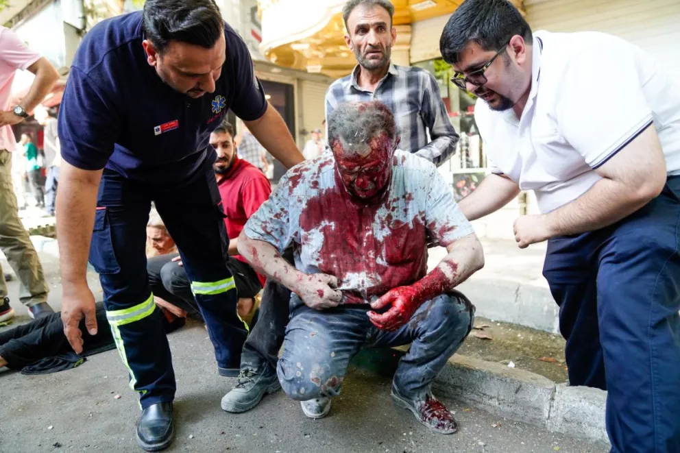 Personas ayudan a un hombre herido tras un ataque aéreo israelí en el centro de Teherán. Foto: EFE