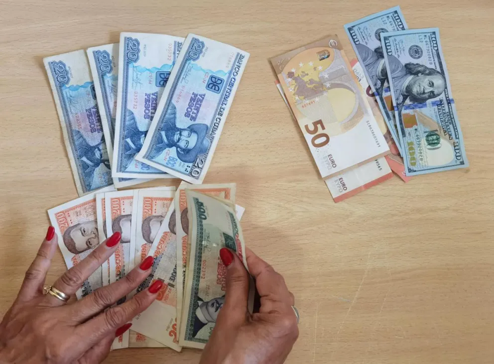 Una persona que muestra billetes de dólares, euros y pesos cubanos en La Habana (Cuba). Foto: EFE