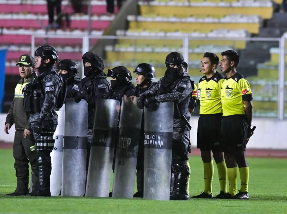 La terna arbitral de campo protegida por efectivos policiales luego del partido. Foto: APG.