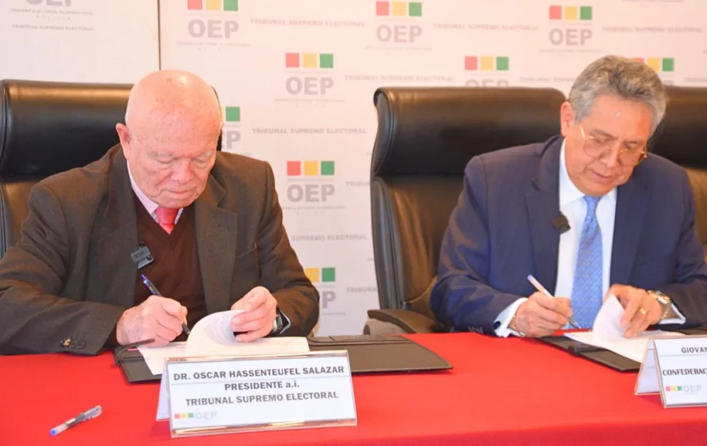 El presidente interino del TSE, Óscar Hassenteufel, y el presidente de la CEPB, Giovanni Ortuño, firman un acuerdo para el debate electoral. Foto: CEPB