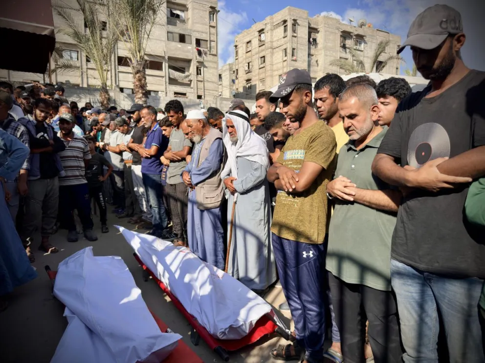 Personas rezan junto a los cadáveres tras la llegada de los cuerpos al Hospital Naser, Foto: EFE