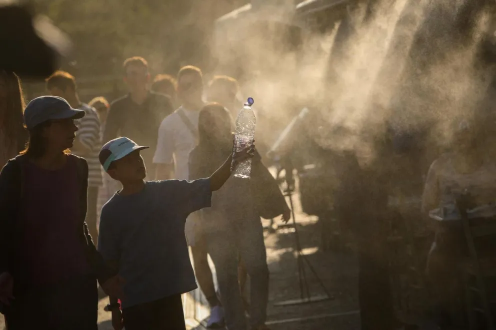 Turistas pasean por Atenas bajo el agua pulverizada por aspersores en la calle debido a las altas temperaturas en Grecia. Foto: EFE