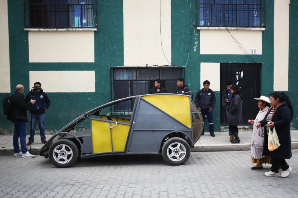 Imagen del 3 de julio de 2025 de personas caminando junto al auto eléctrico 'Katari MRC5' en El Alto (Bolivia). Foto: EFE