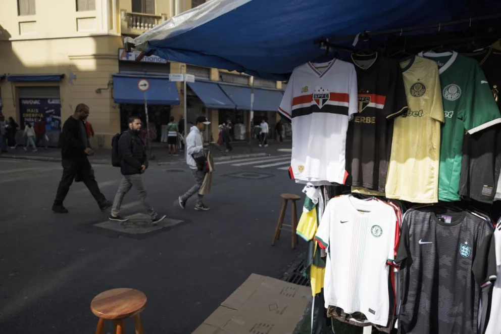Personas caminan junto a mercancía exhibida en una calle del comercio la Rua 25 de Março, en São Paulo (Brasil). Foto: EFE