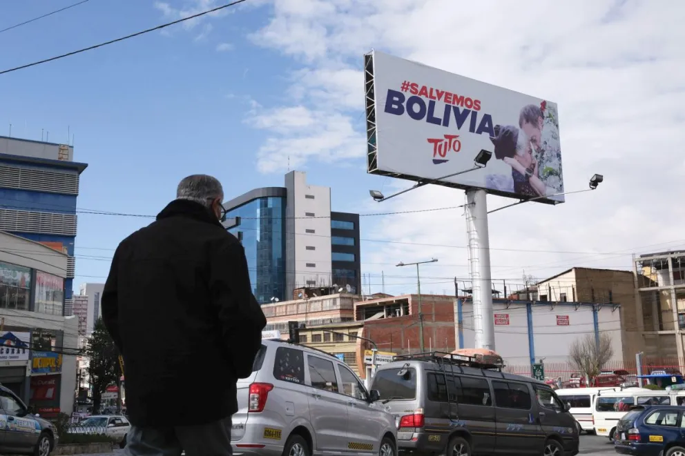 Una persona camina frente a un cartel del candidato a la presidencia por Alianza Libre, Jorge Quiroga este 17 de julio de 2025, en La Paz. Foto: EFE