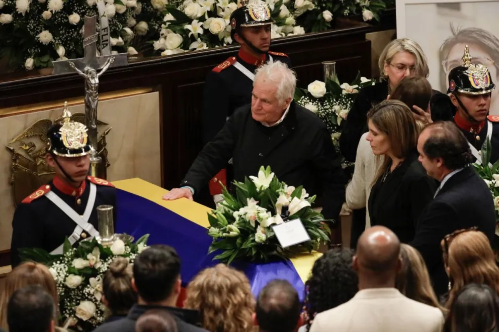 El padre del fallecido senador y precandidato a la presidencia de Colombia Miguel Uribe Turbay, Miguel Uribe, toca el féretro de Miguel. Foto EFE