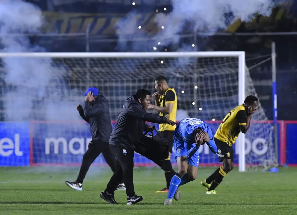 Jugadores de The Strongest y Blooming se protegen cuando los fuegos artificiales llegan a la cancha del Siles. Foto: APG
