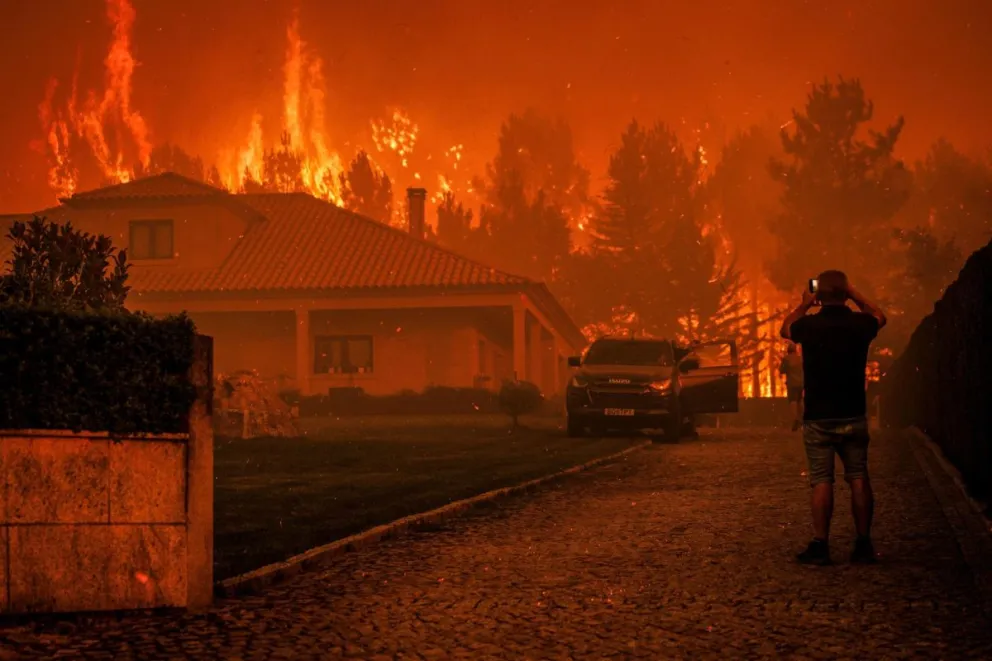 Un hombre observa cómo un incendio forestal se desata cerca de una casa en Granja do Paiva, municipio de Sernancelhe. Foto: EFE