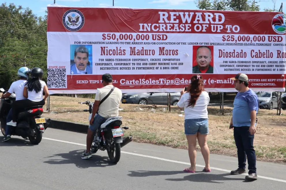 Personas observan, en Colombia, la valla con la imagen del presidente y del ministro de Relaciones Interiores, Justicia y Paz de Venezuela. Foto: EFE