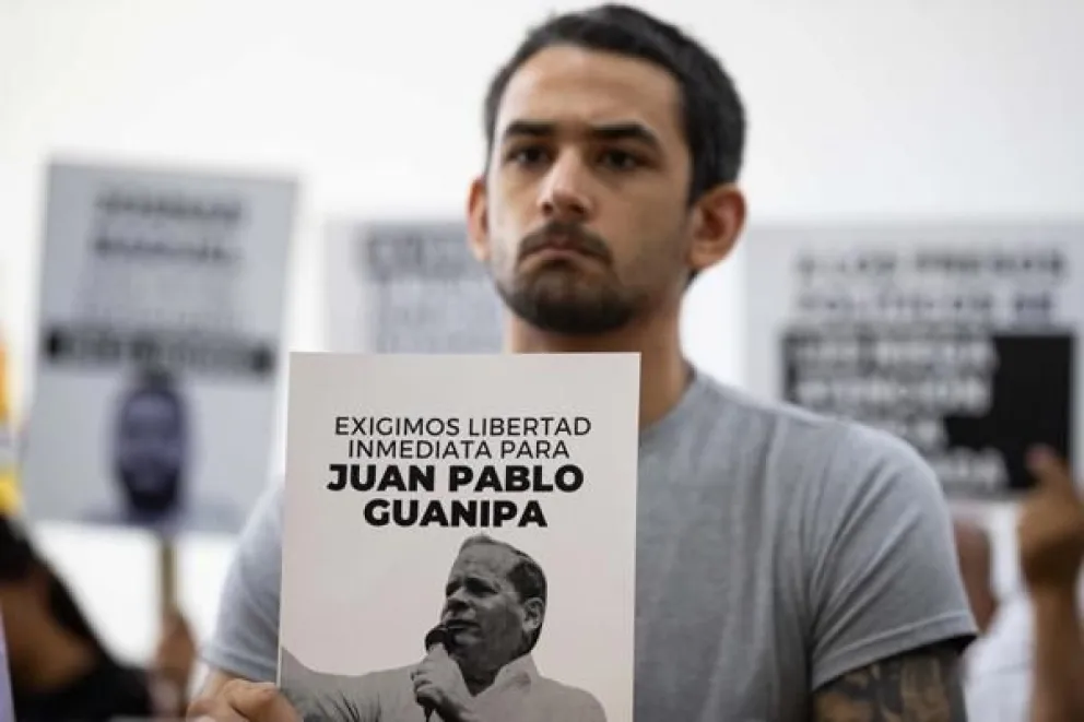 Ramón Guanipa sostiene un cartel de su padre detenido, Pedro Guanipa, en una imagen reciente. . EFE/Ronald Peña R