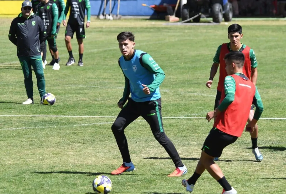 Moisés Villarroel (rojo) le pega a la pelota ante la marca de Leonardo Zabala (celeste). También participa Marcelo Torrez y metros atrás observa Oscar Villegas, el DT. Foto: Marka Registrada