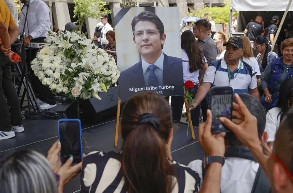 Personas toman fotografías a una imagen del fallecido senador y precandidato de Colombia Miguel Uribe Turbay. Foto: EFE