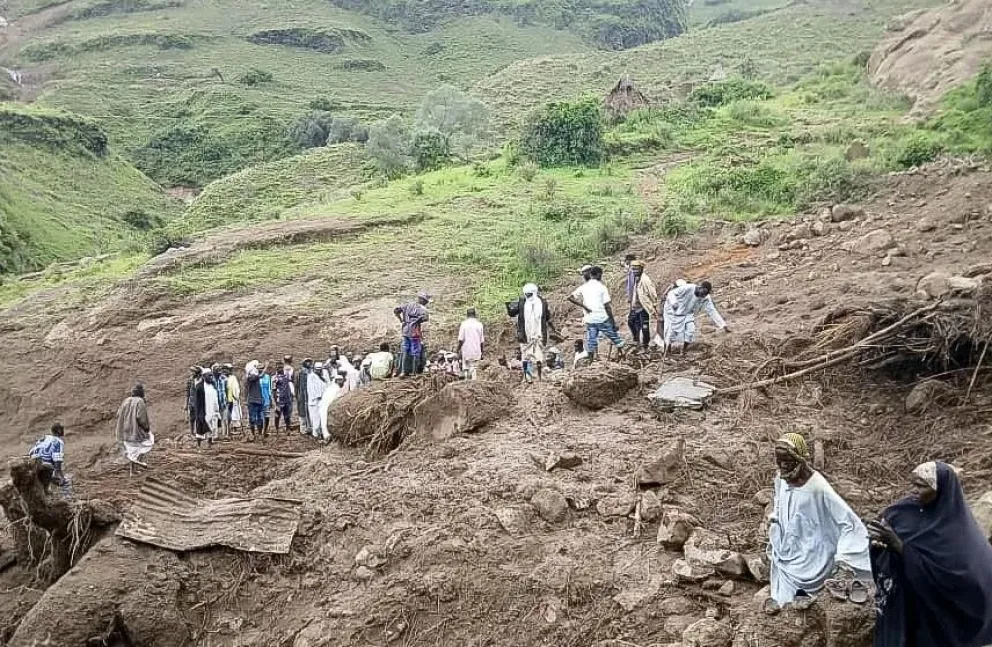 Personas caminan en medio del deslizamiento de tierra en Tarsin. Foto: EFE
